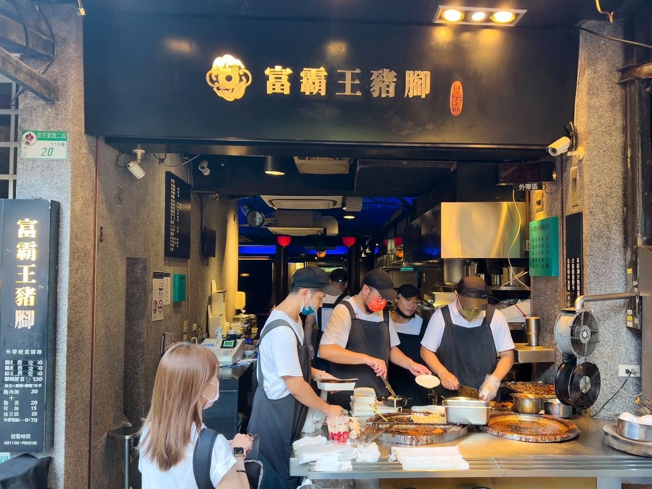 Staff plate orders at Fu Ba Wang Pork Knuckle's open storefront beneath the gold 富霸王豬腳 sign.