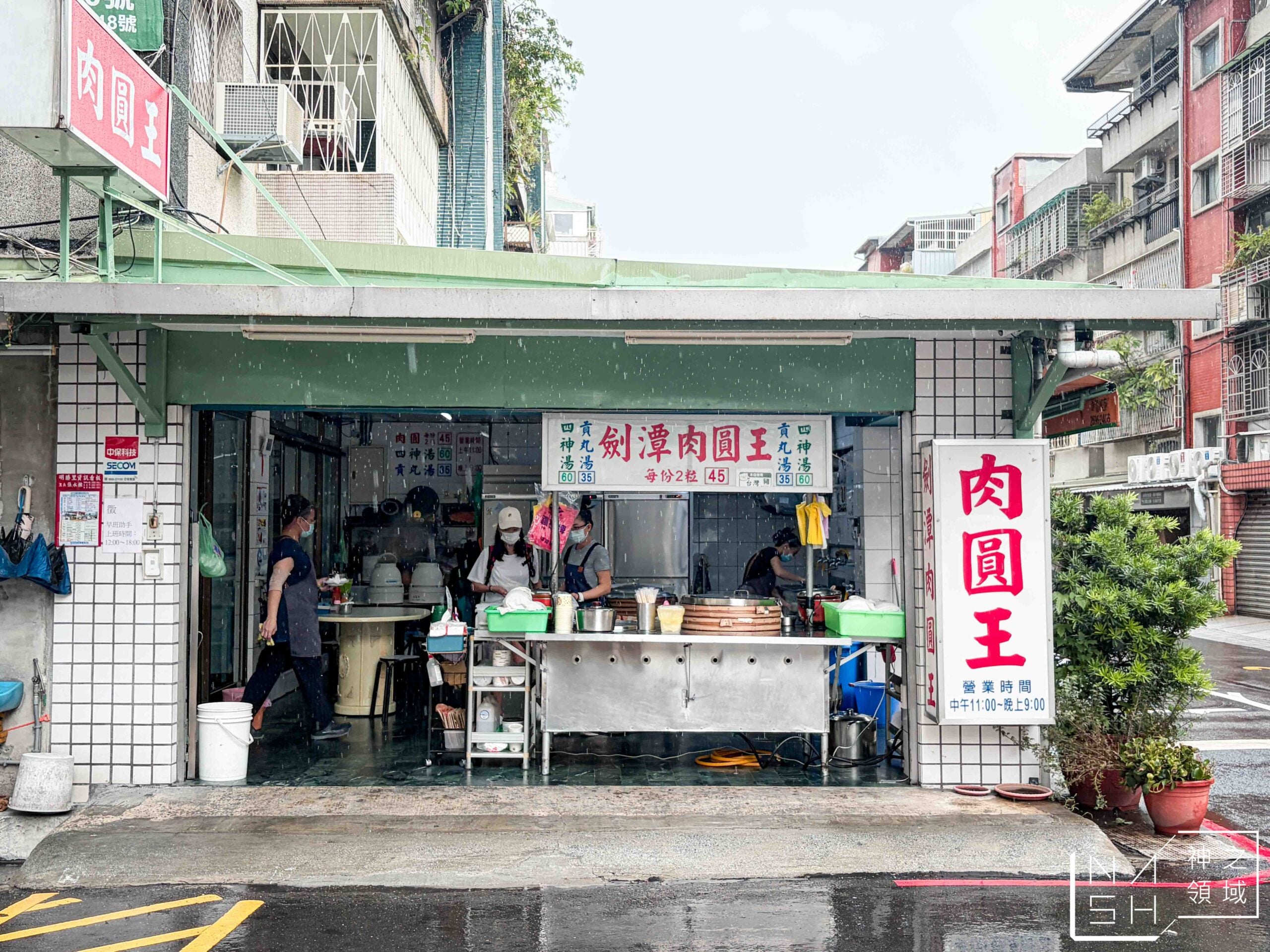 The open storefront of Jiantan Rouyuan Wang on a rainy day, with Chinese signs and bamboo steamers visible at the counter.